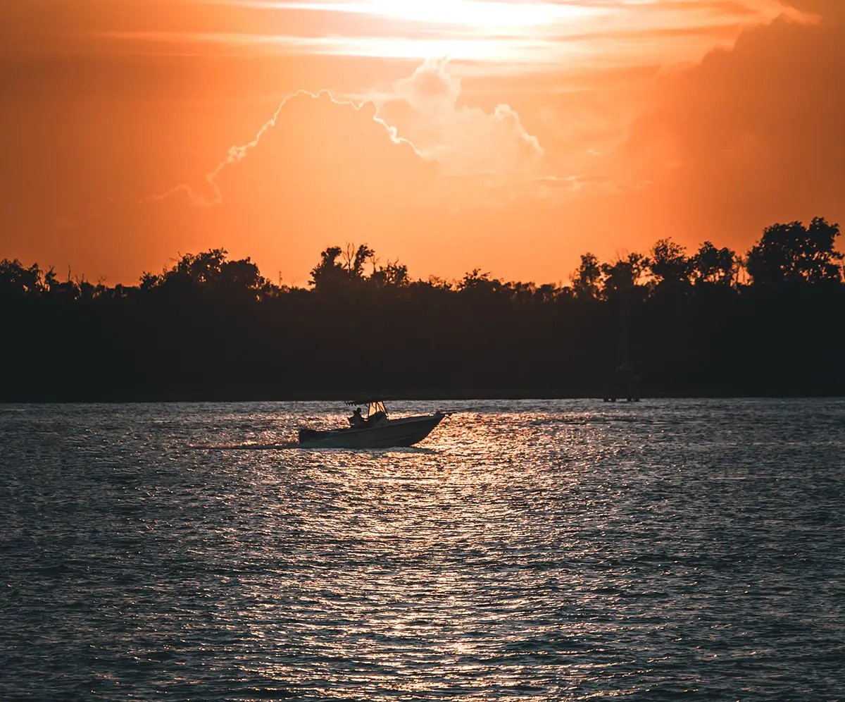 photograph of a boat sailing at sunset