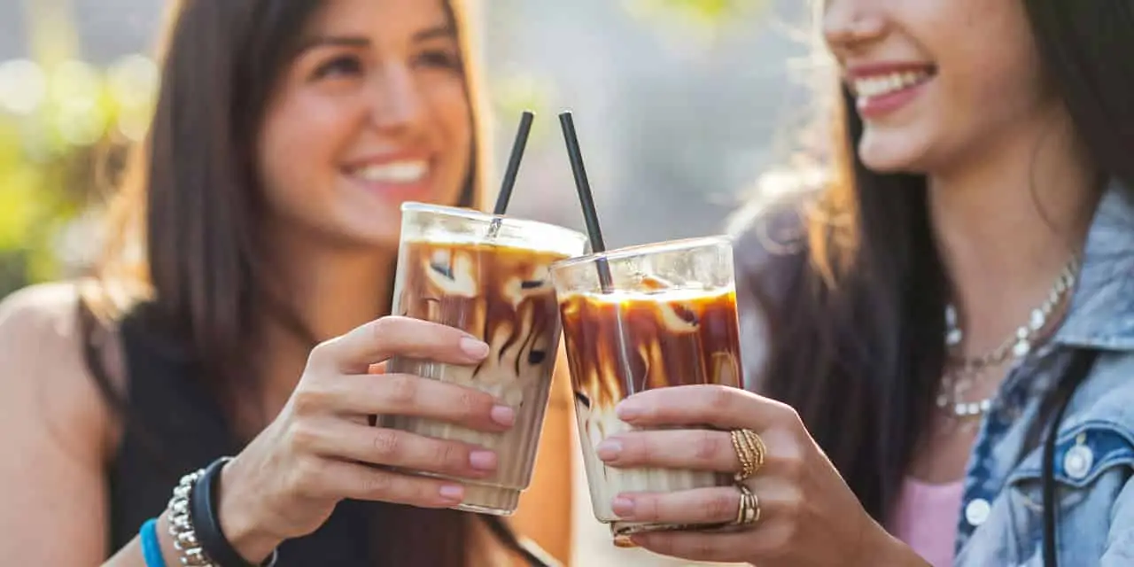 two smiling women drinking ice coffee