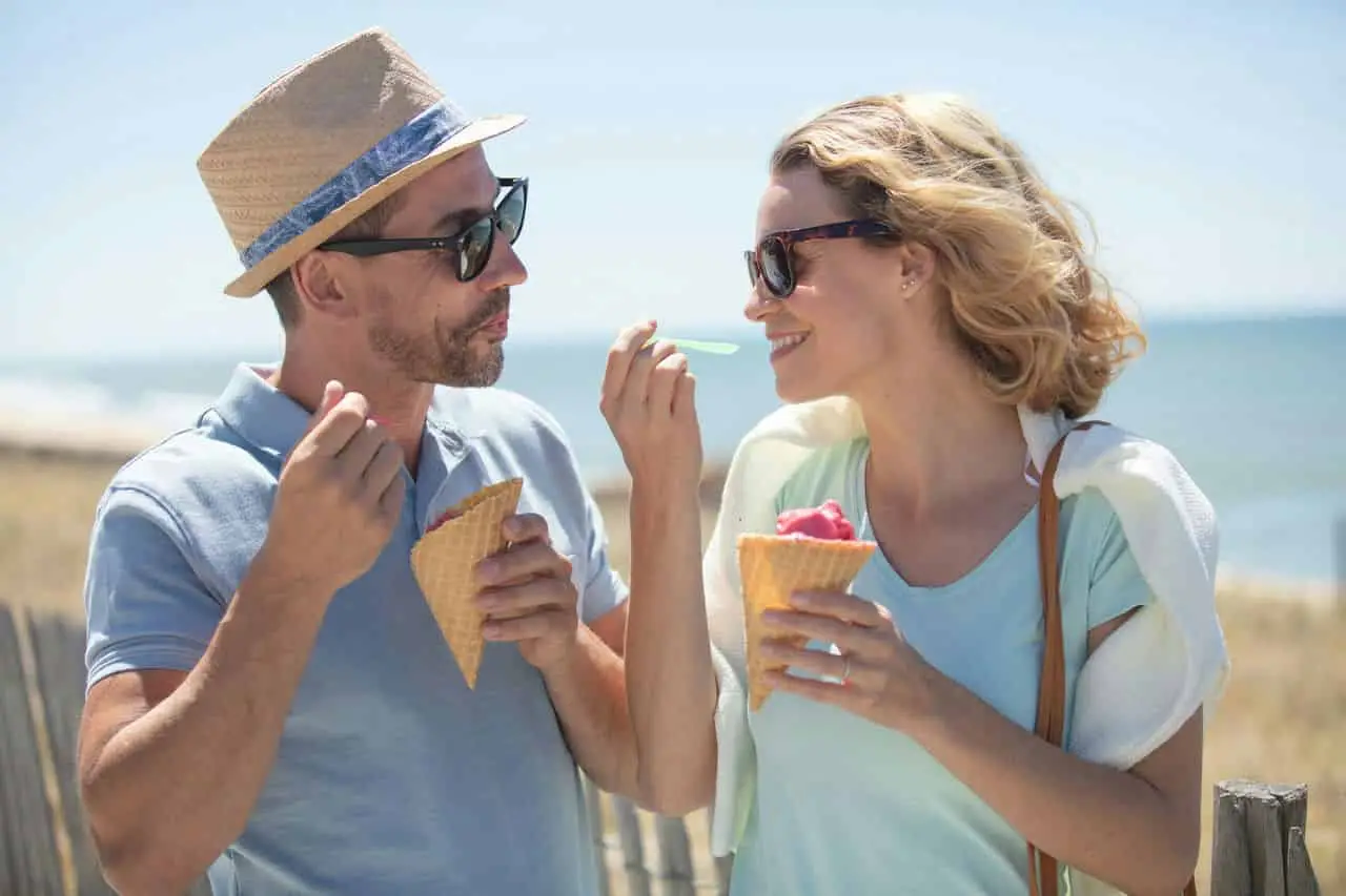 smiling couple sharing ice cream cones on a sunny day